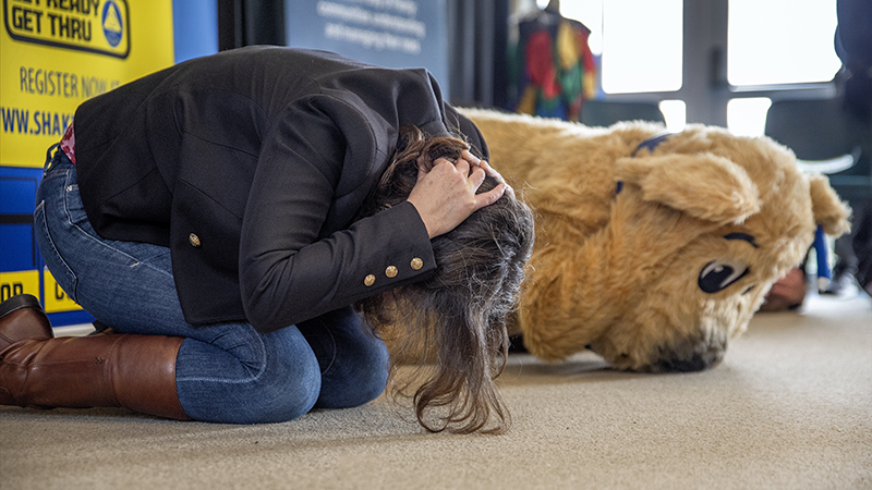Woman and Stan the dog doing Drop, Cover and Hold