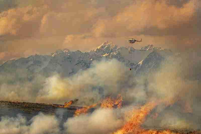Helicopter with a monsoon bucket over a large wildfire