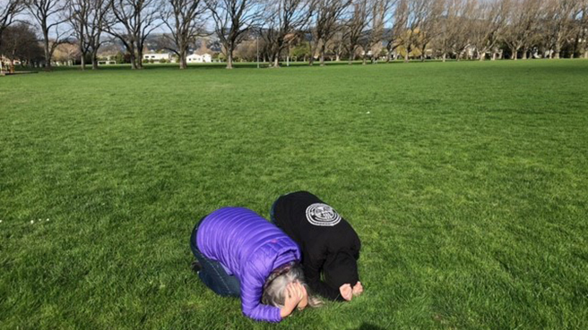 Two people doing Drop, Cover and Hold outside